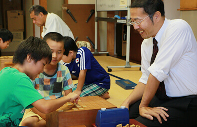 飛世将棋道場KUROBEで、子供達と将棋を指す桶屋郁夫さん